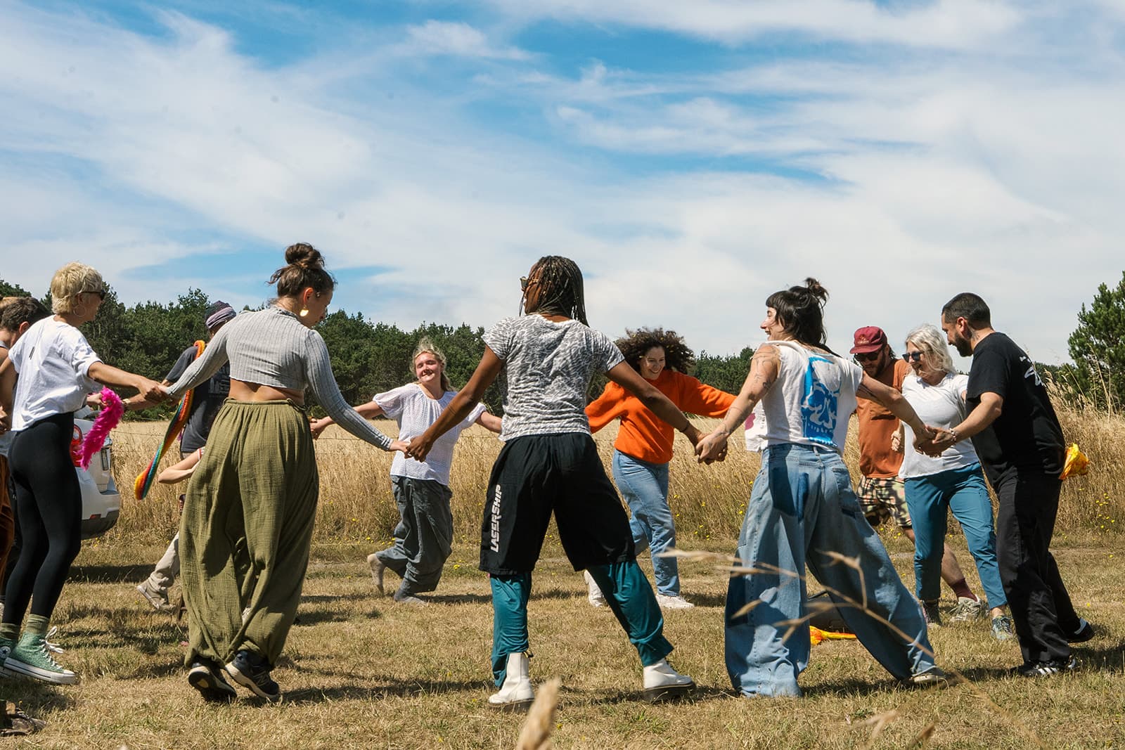 Campers holding hands in a circle, dancing in a sunny field