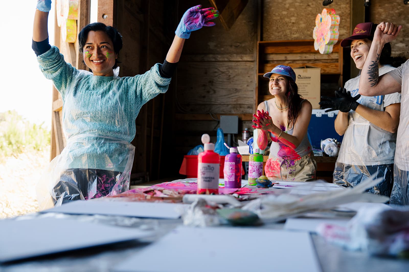A painter throwing her arms up in joy at the paint table