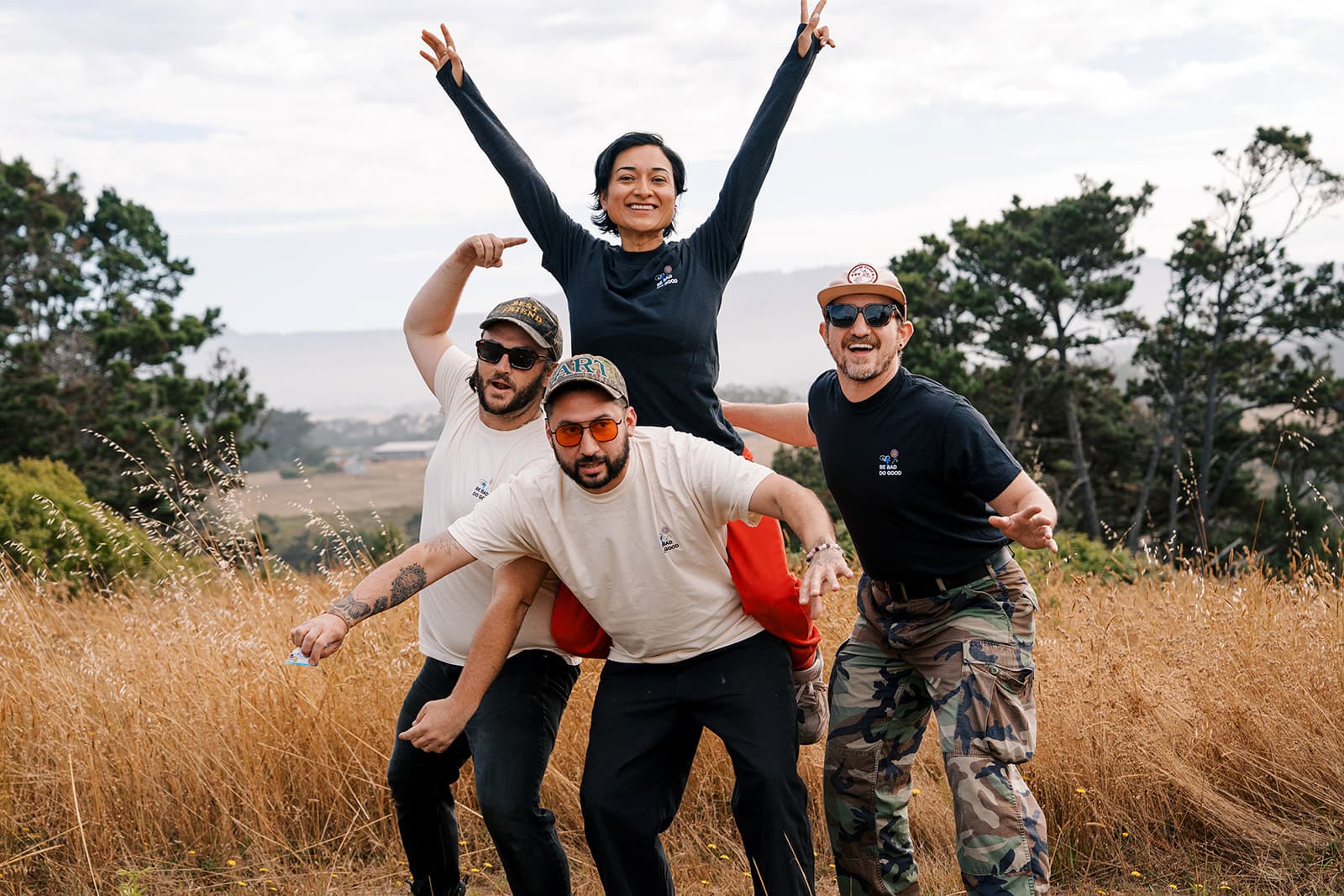 Four campers goofing around in Bad Art Club merch in a golden field