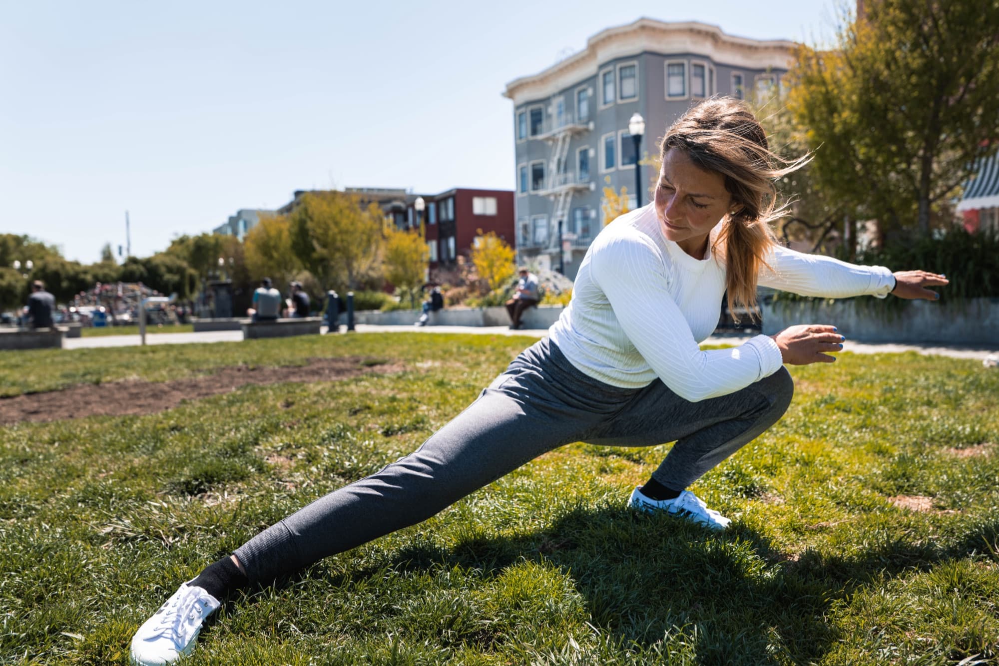 Fabiana mid-movement, stretching low in a park.