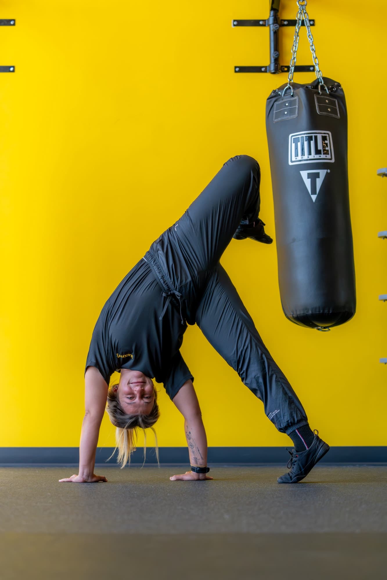 Fabiana in a dynamic movement pose beside a boxing bag.