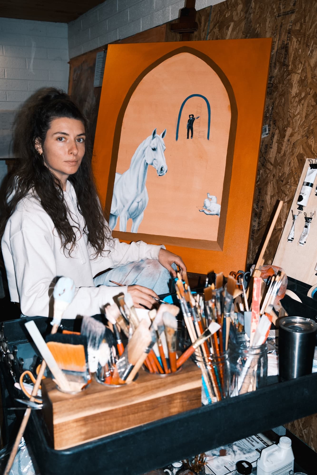 Taylor at her easel, painting a horse.