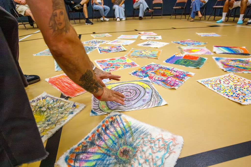 All 38 self-portrait artworks laid out across the gymnasium floor in a circle for the witnessing exercise