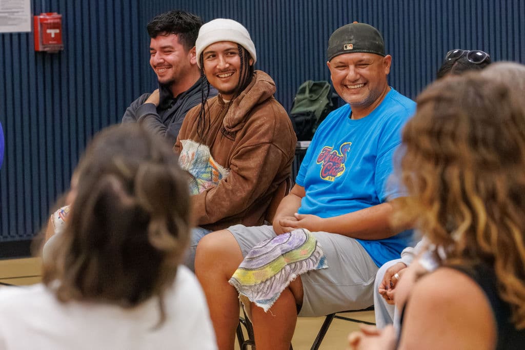 Three staff members laughing together, one cradling his artwork