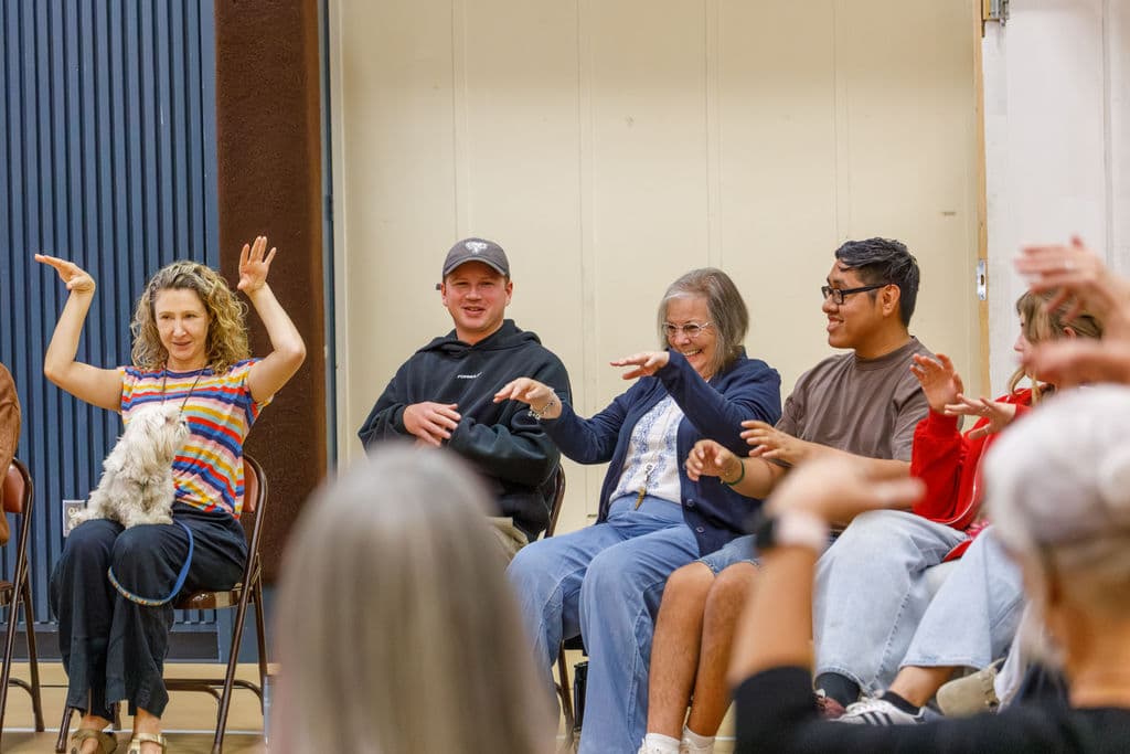 Four staff members doing a synchronized hand gesture movement activity, smiling