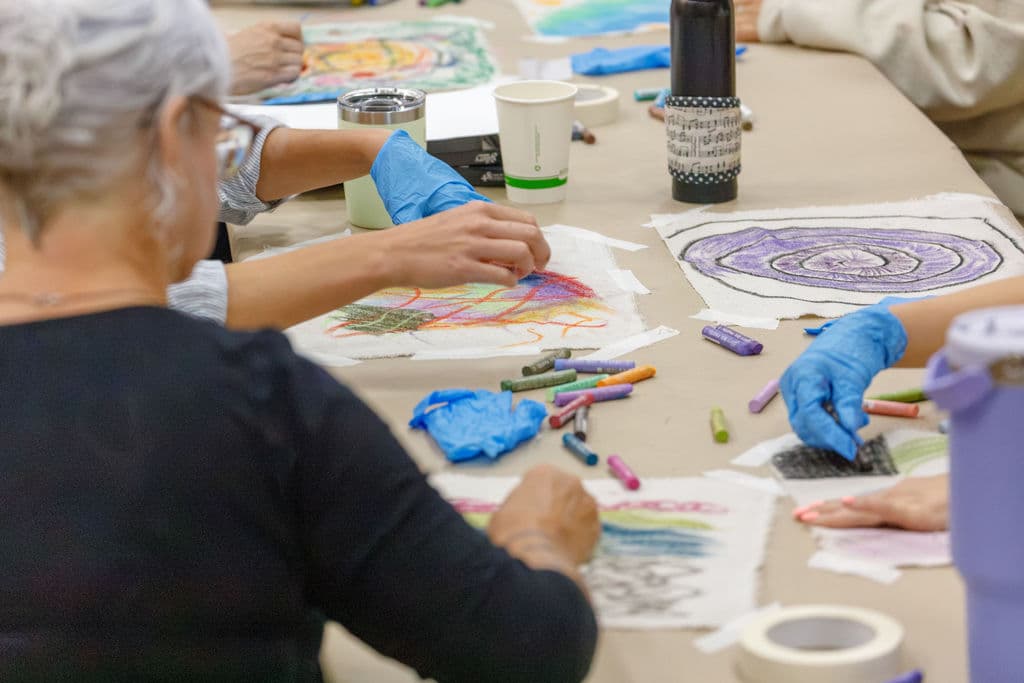 Close-up of hands working with pastels on drop cloth self-portraits
