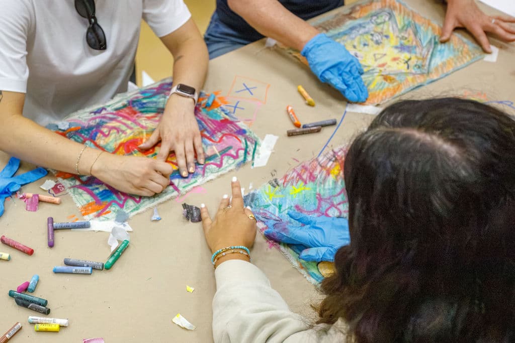 Overhead view of staff creating pastel self-portraits spread across a table