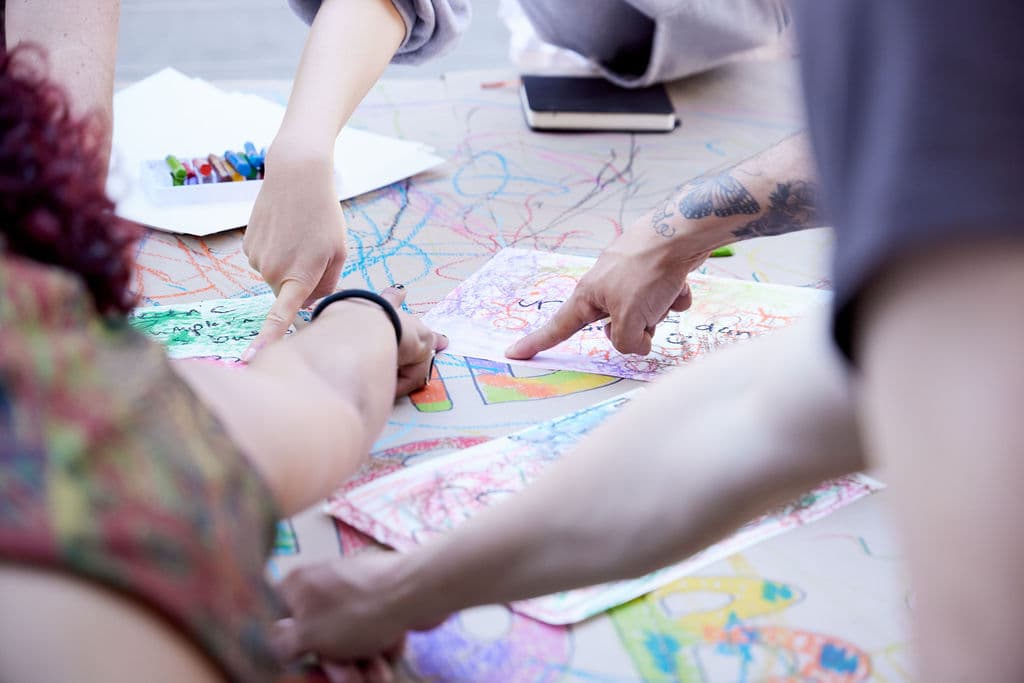 Hands pointing at collaborative drawings spread across a table