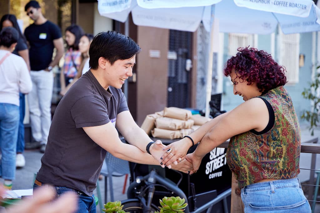 Two people clasping hands and laughing during a connection activity