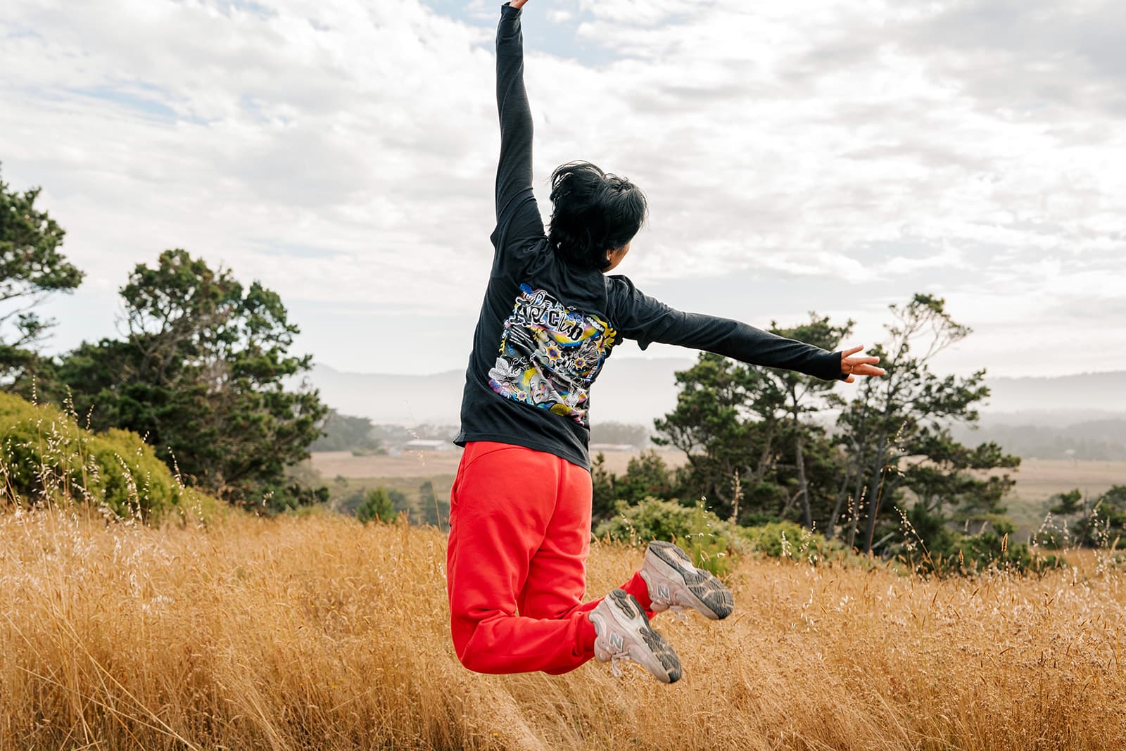 Person leaping mid-air wearing a Bad Art Club long-sleeve