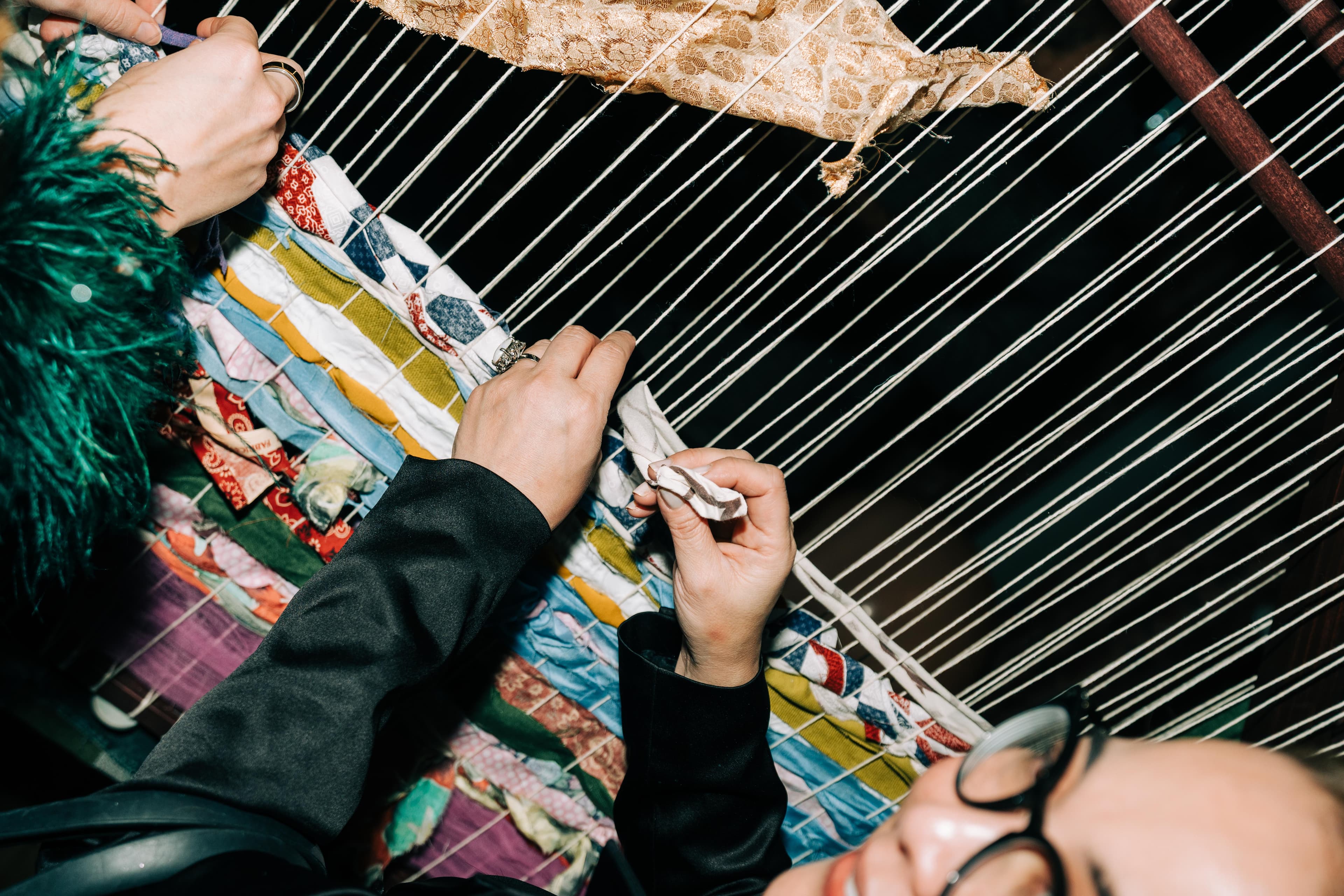 Hands weaving into communal loom