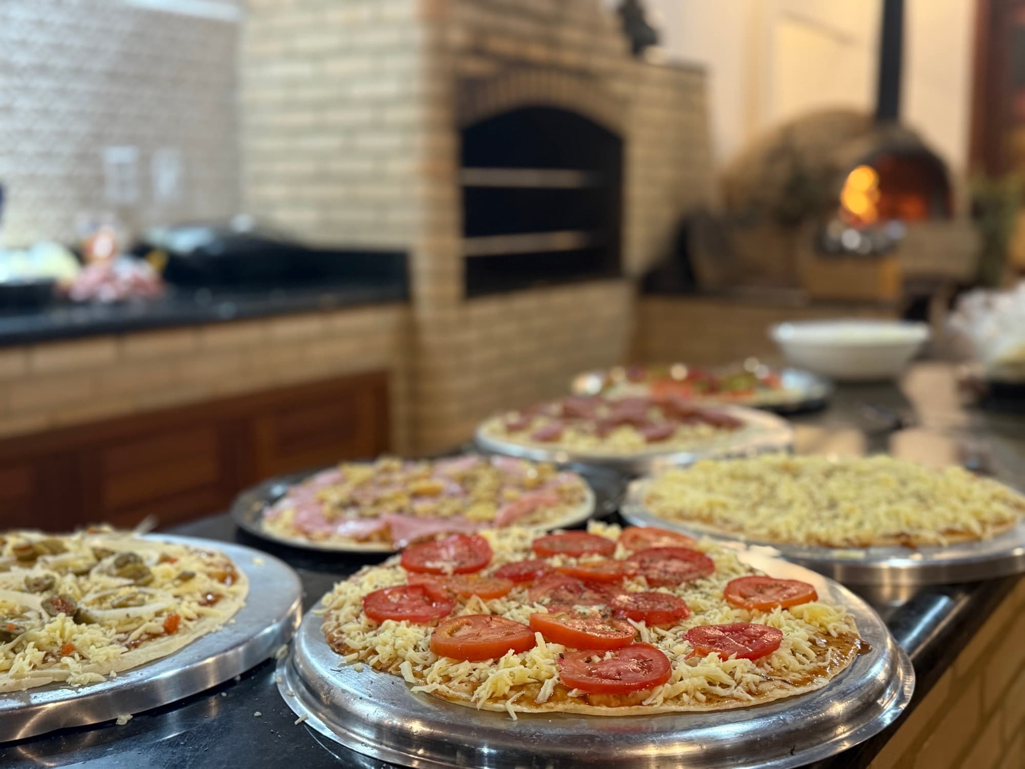 Fresh pizzas lined up by the wood-fired brick oven.